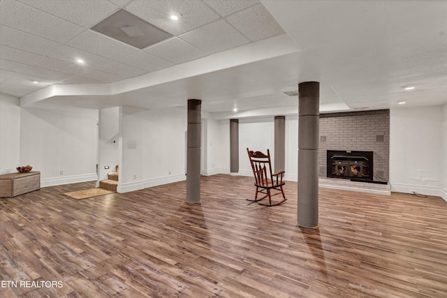 basement with a fireplace, hardwood / wood-style floors, and a drop ceiling