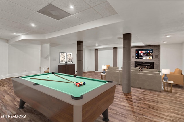 rec room featuring a fireplace, hardwood / wood-style flooring, a drop ceiling, and billiards