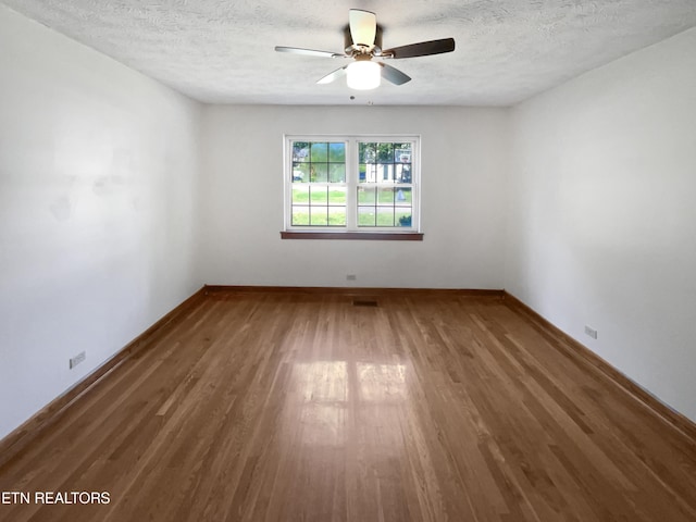 empty room with ceiling fan, dark hardwood / wood-style flooring, and a textured ceiling