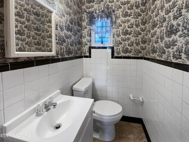 bathroom with tile patterned flooring, vanity, toilet, and tile walls