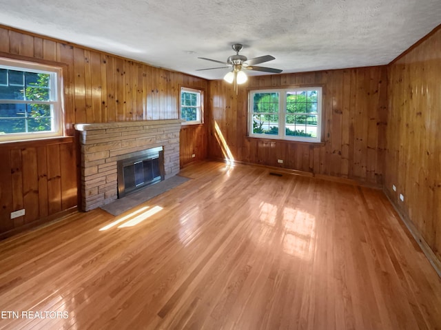 unfurnished living room with hardwood / wood-style flooring, wood walls, and a fireplace