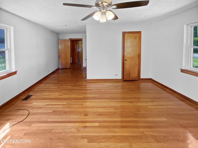 empty room with light wood-type flooring, plenty of natural light, and ceiling fan