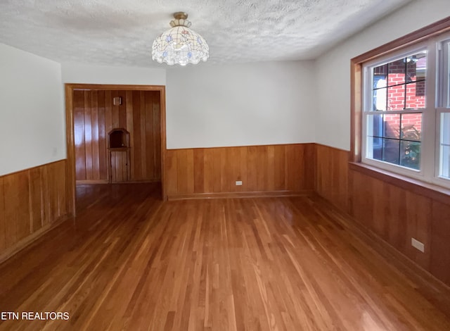 spare room featuring hardwood / wood-style floors, a textured ceiling, and an inviting chandelier