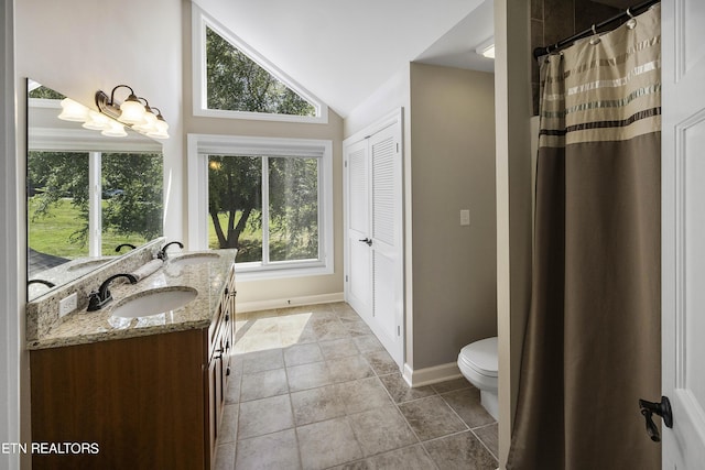 bathroom featuring double vanity, toilet, lofted ceiling, and a sink