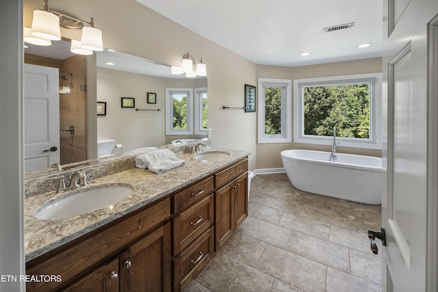 full bathroom featuring double vanity, a freestanding tub, visible vents, and a sink