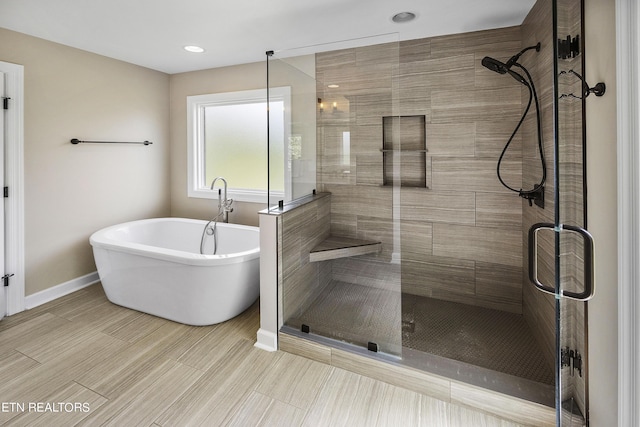 full bathroom featuring a soaking tub, baseboards, and a stall shower