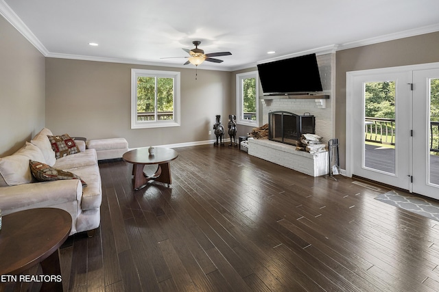 living room with a ceiling fan, a brick fireplace, dark wood-style floors, and crown molding