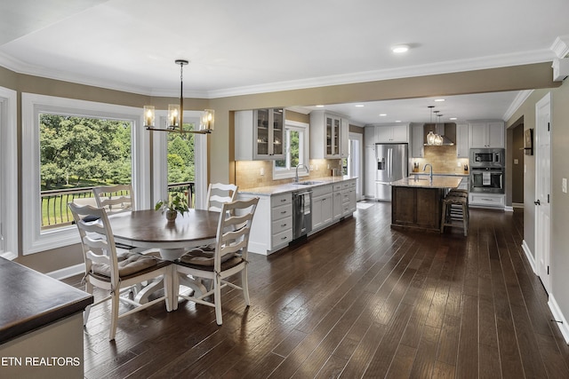 dining room featuring a notable chandelier, ornamental molding, dark wood finished floors, recessed lighting, and baseboards