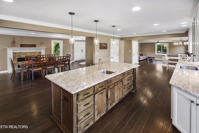 kitchen with dark wood finished floors, open floor plan, an island with sink, and a sink