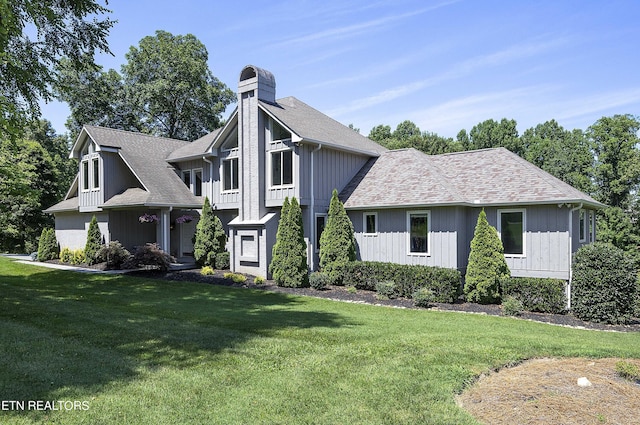 view of front facade featuring a front lawn, a chimney, and a shingled roof