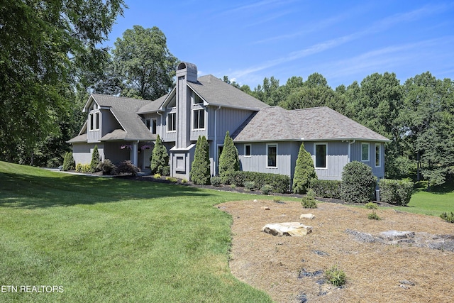 view of front of property with a shingled roof, a front yard, board and batten siding, and a chimney