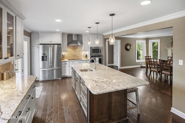 kitchen featuring ornamental molding, a sink, appliances with stainless steel finishes, wall chimney range hood, and tasteful backsplash