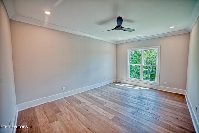 empty room with a ceiling fan, crown molding, baseboards, and wood finished floors