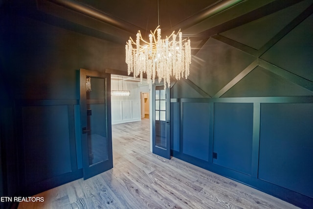 bonus room with a decorative wall, a notable chandelier, and wood finished floors