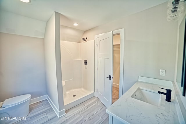 bathroom with baseboards, a shower stall, toilet, and vanity