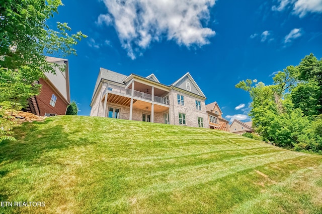 back of property with a yard and a balcony