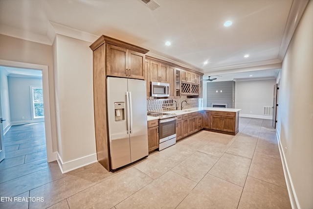 kitchen featuring stainless steel appliances, a sink, light countertops, ornamental molding, and decorative backsplash