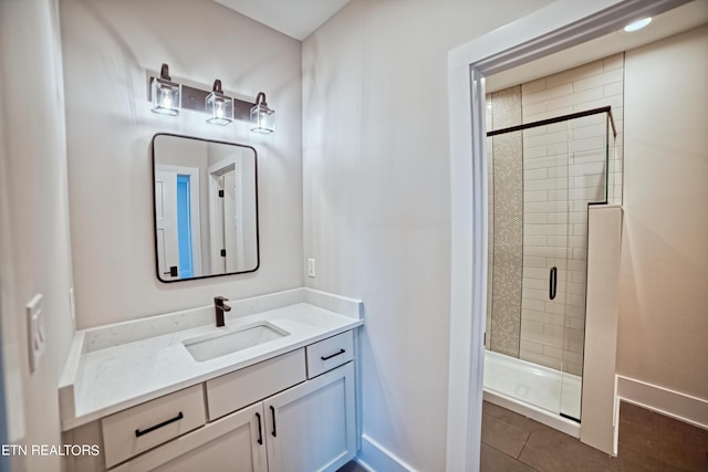 bathroom with tile patterned floors, a shower stall, baseboards, and vanity