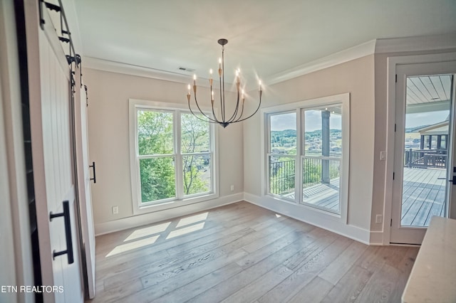 unfurnished dining area featuring a barn door, a notable chandelier, wood finished floors, visible vents, and crown molding