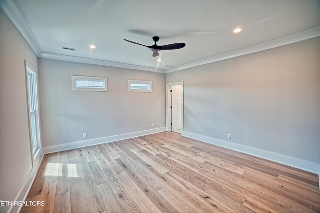 spare room featuring ceiling fan, light wood-style flooring, visible vents, baseboards, and crown molding