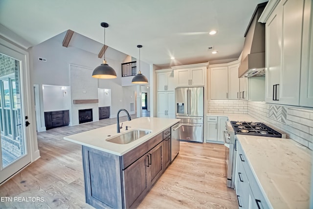 kitchen featuring stainless steel appliances, light countertops, a sink, and light wood-style flooring