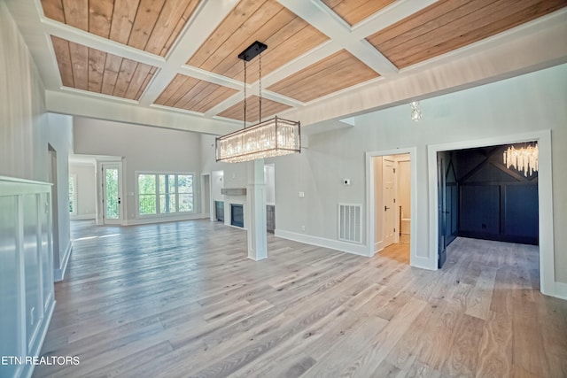 unfurnished living room with visible vents, coffered ceiling, a glass covered fireplace, wooden ceiling, and wood finished floors