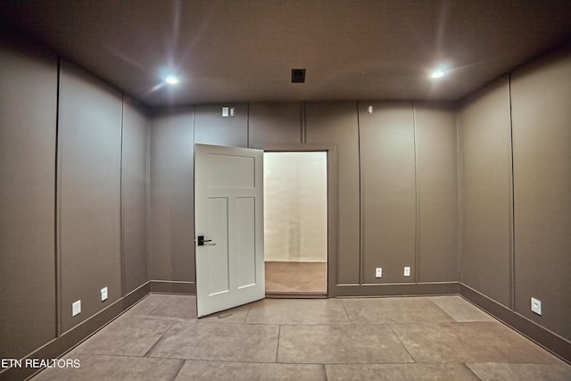 spare room with light tile patterned floors and a decorative wall