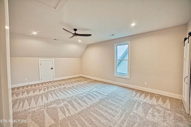 bonus room featuring a barn door, visible vents, baseboards, lofted ceiling, and carpet