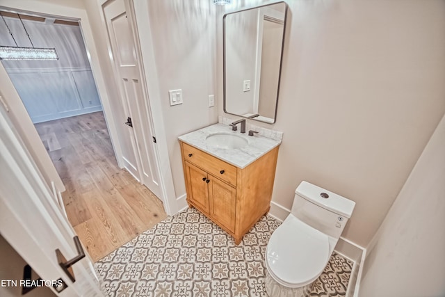 half bathroom with toilet, wood finished floors, and vanity