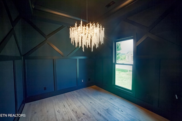 bonus room with a notable chandelier, wood finished floors, and a decorative wall