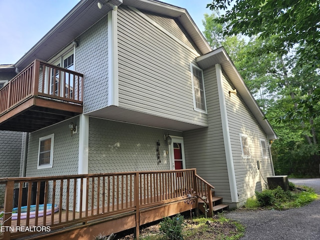 view of side of property featuring a balcony and a wooden deck