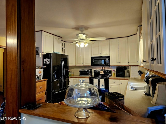 kitchen with kitchen peninsula, white cabinets, and black appliances