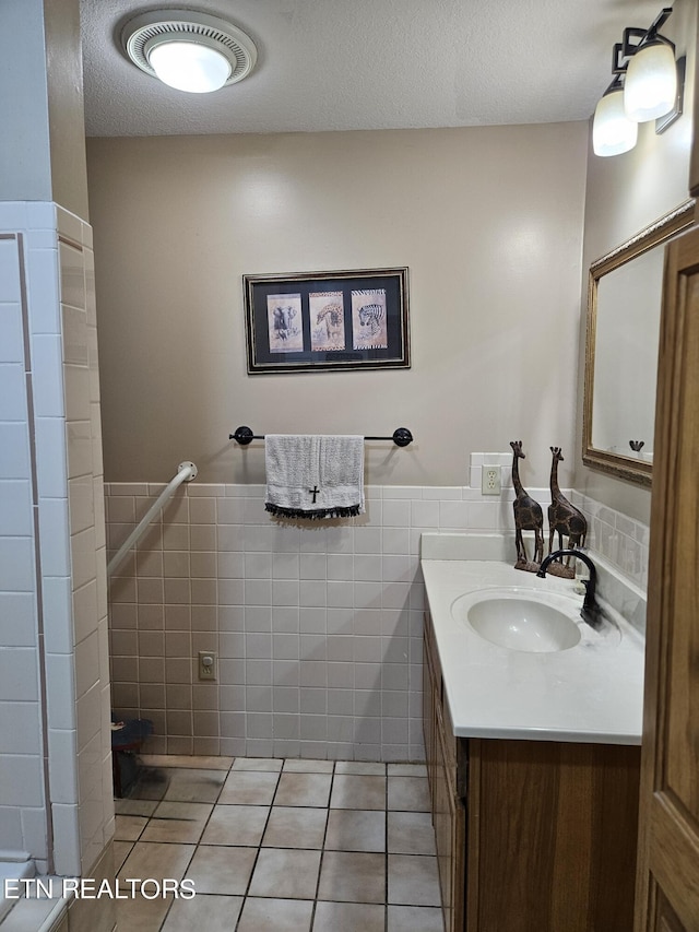 bathroom with a textured ceiling, tile patterned flooring, vanity, and tile walls