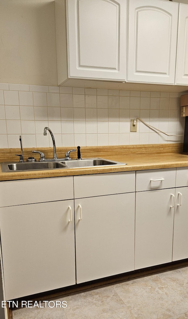 kitchen featuring decorative backsplash, white cabinetry, and sink