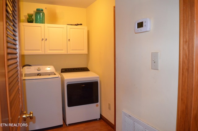 laundry area featuring cabinets, hardwood / wood-style flooring, and washer and dryer