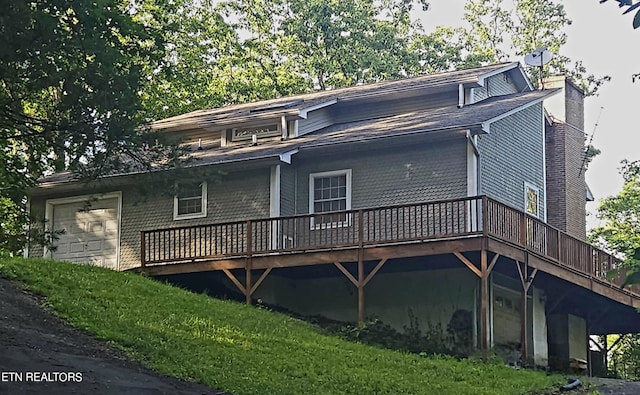 rear view of property with a garage, a yard, and a wooden deck