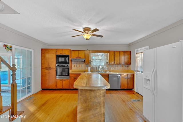 kitchen featuring light hardwood / wood-style flooring, stainless steel dishwasher, white refrigerator with ice dispenser, and plenty of natural light