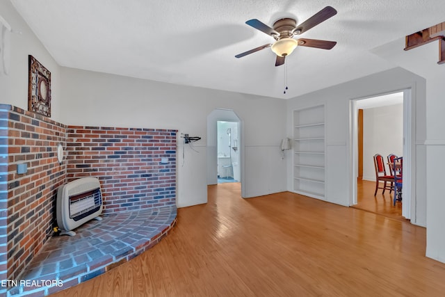 unfurnished living room with light hardwood / wood-style flooring, a textured ceiling, heating unit, and ceiling fan