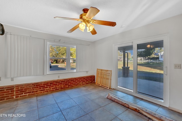 tiled empty room with brick wall and ceiling fan