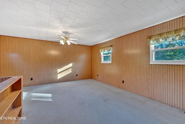 spare room with wooden walls, ceiling fan, and plenty of natural light