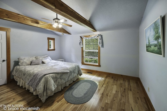 bedroom featuring ceiling fan, vaulted ceiling with beams, and light hardwood / wood-style flooring