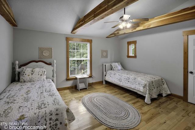 bedroom with ceiling fan, lofted ceiling with beams, light wood-type flooring, and a textured ceiling