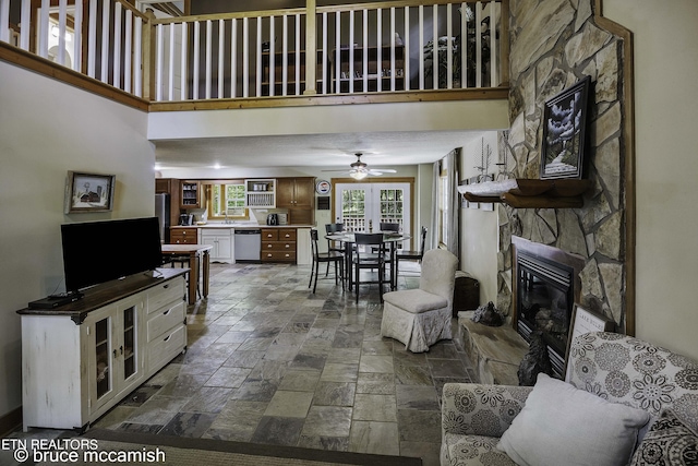 living room featuring ceiling fan, a fireplace, and a high ceiling