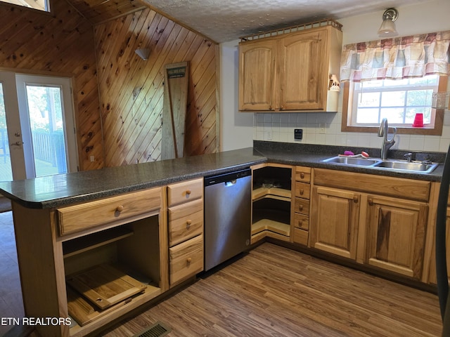 kitchen with sink, wooden walls, stainless steel dishwasher, dark hardwood / wood-style floors, and kitchen peninsula