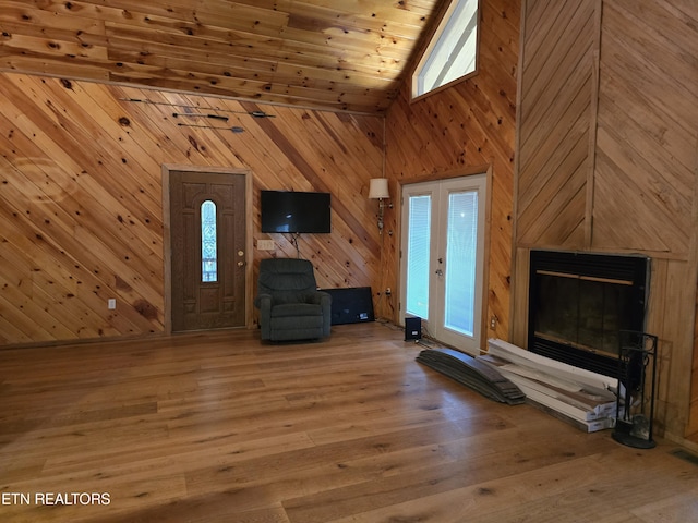 unfurnished living room with french doors, high vaulted ceiling, hardwood / wood-style floors, wooden walls, and wood ceiling