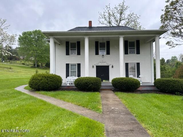 696 Forge Ridge Rd, Harrogate, TN 37752 - greek revival inspired property with a front yard, a chimney, covered porch, and stucco siding