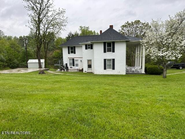 back of house with an outbuilding and a yard