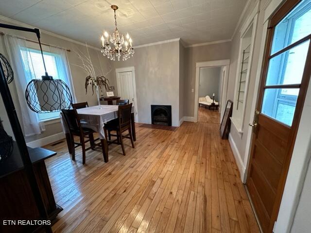 dining space featuring ornamental molding, light hardwood / wood-style flooring, and a notable chandelier