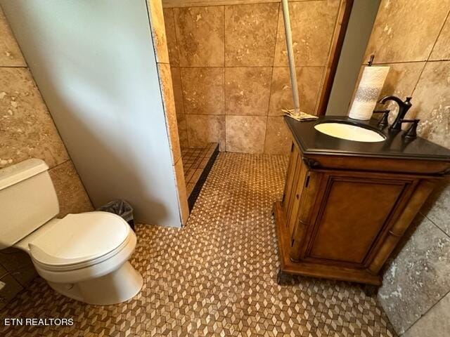 bathroom with vanity, tile walls, and toilet