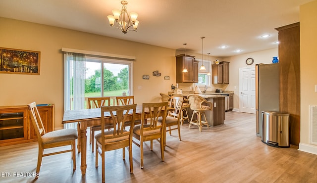 dining space featuring light wood-type flooring and an inviting chandelier